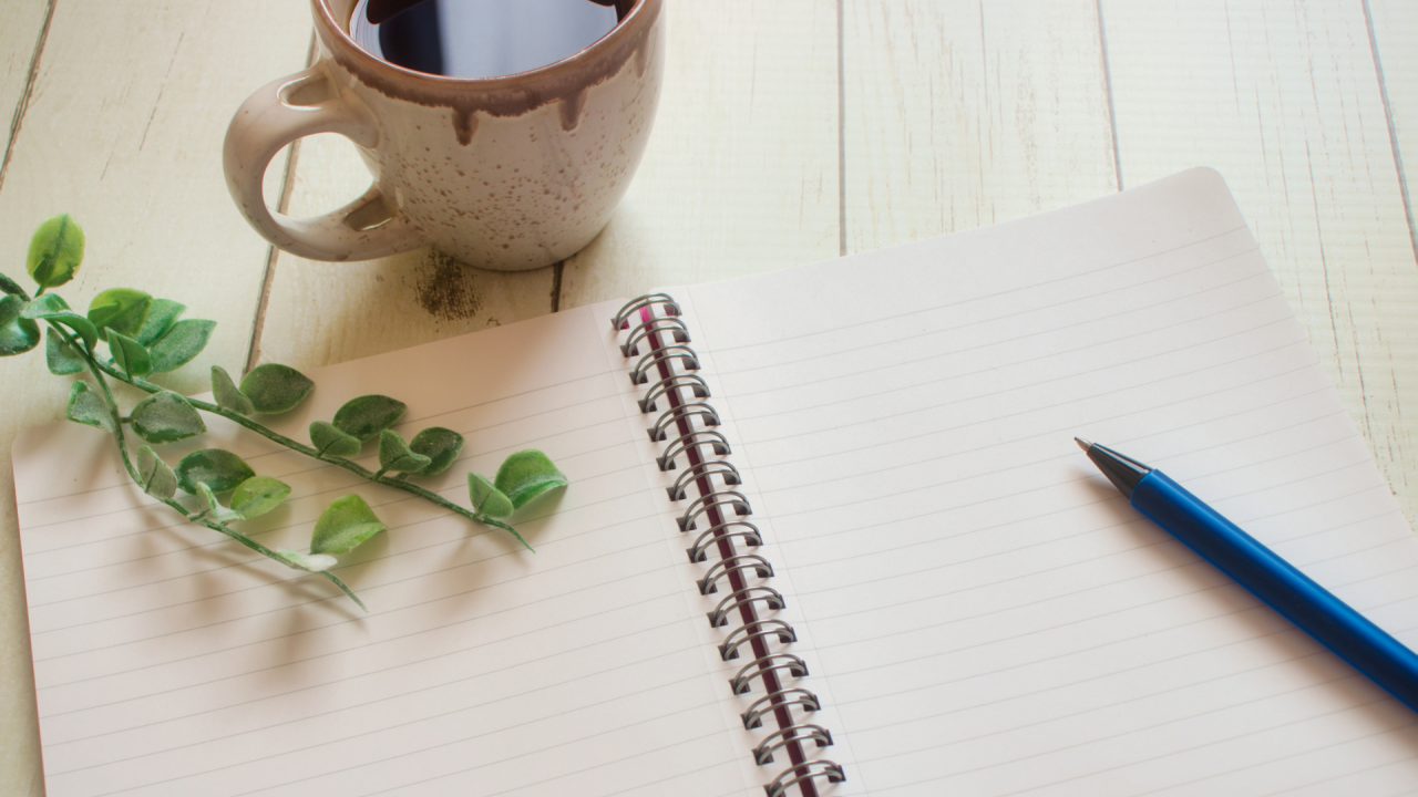 机の上のコーヒーとノートとペン