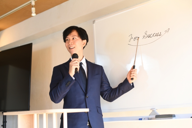 スーツ着ている男性が、解説している写真