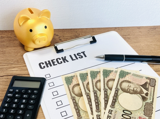 金の豚の貯金箱と電卓と5万円の写真