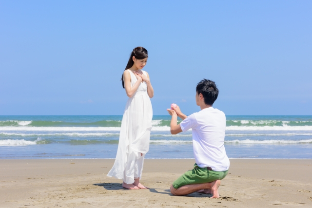 砂浜で男性が女性にプロポーズをしている写真